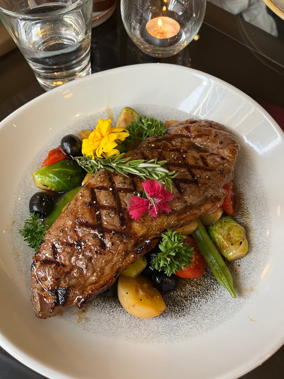 Grilled steak with vegetables and edible flowers